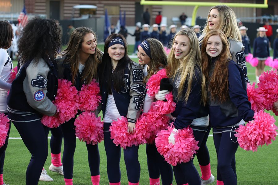 Varsity cheerleaders gather at a football game.