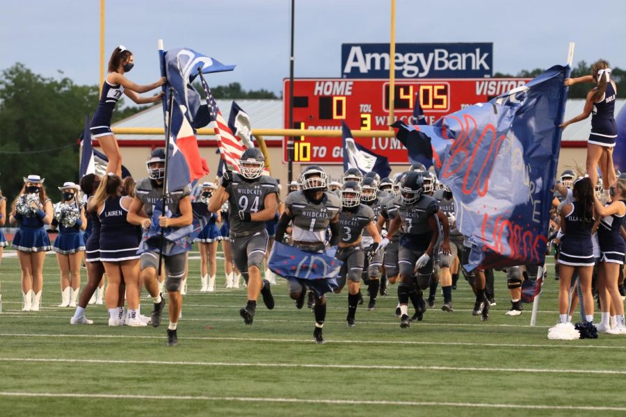 Varsity football players run through a sign at the start of the first game. 