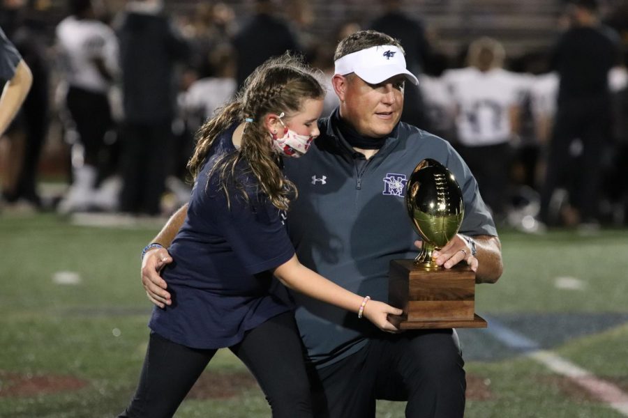 A coach carries the teams trophy after the game.