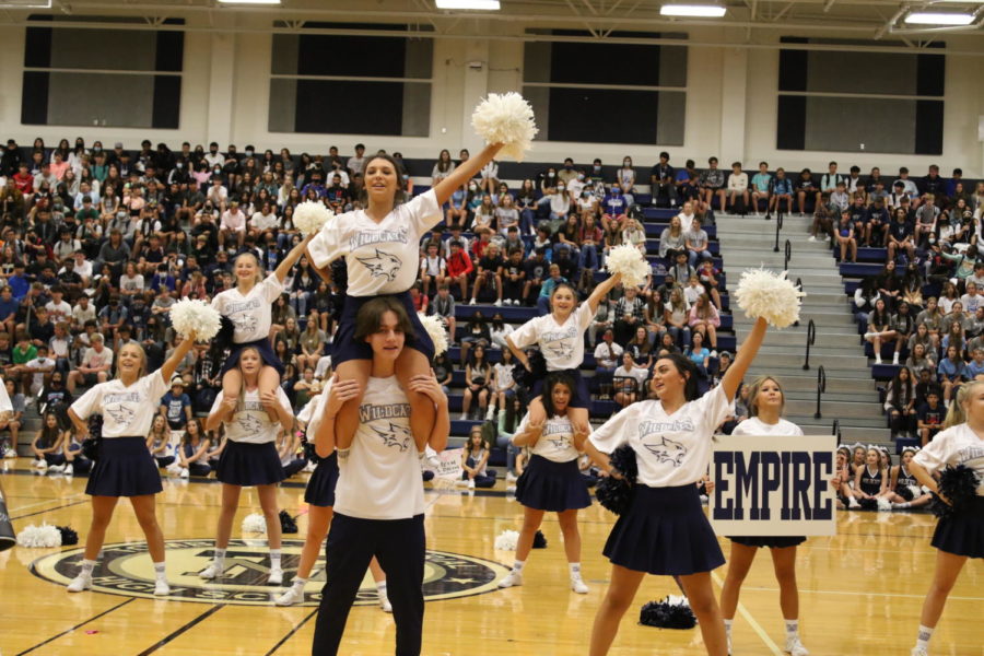 The varsity cheerleaders rally with the crowd to get them hyped for the game. 